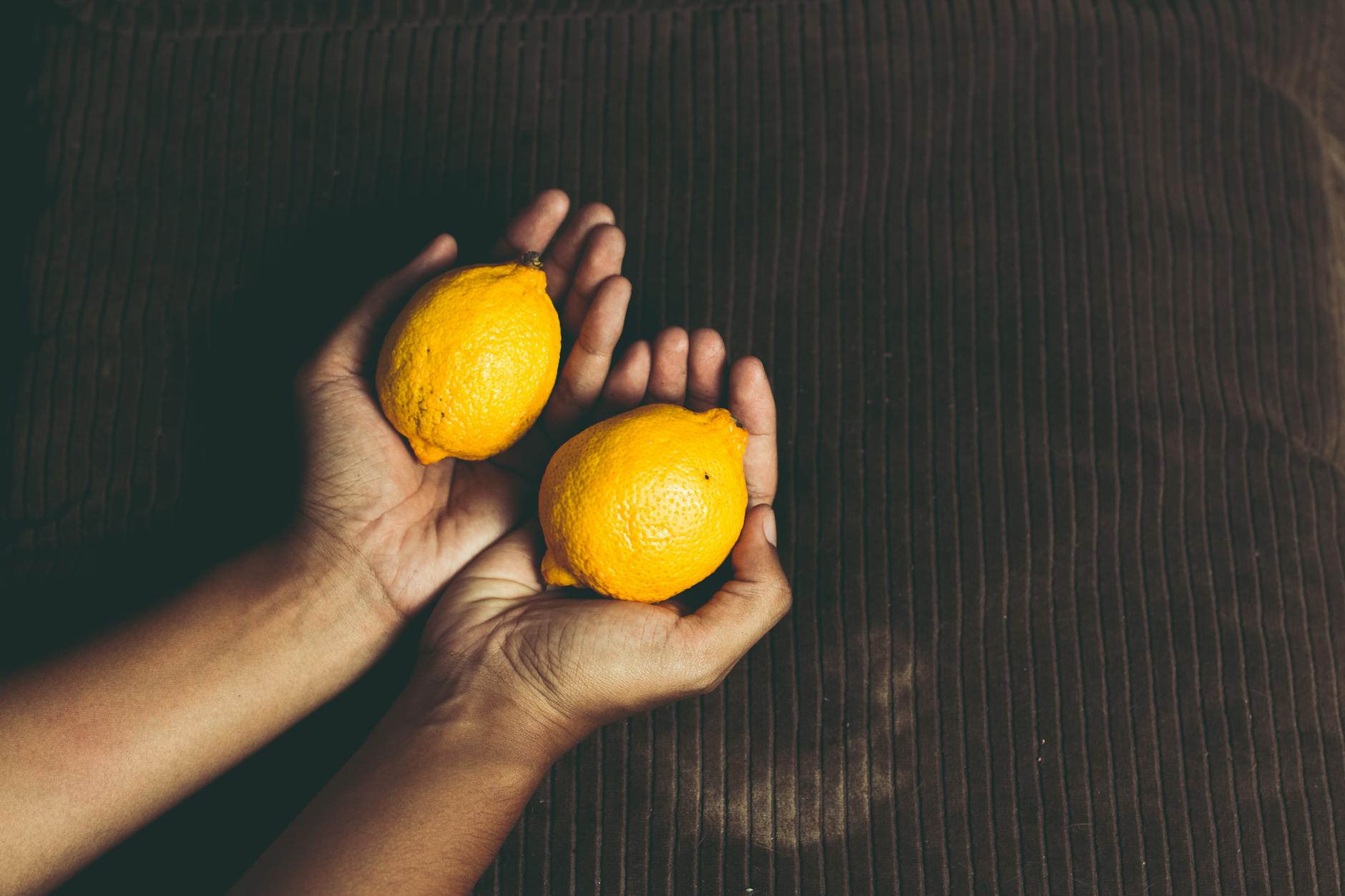Hands holding a sleek blue lemon vibrator against a purple background