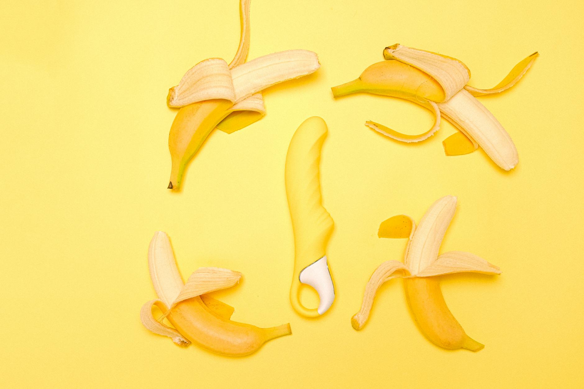 Yellow lemon clitoral vibrator displayed on a warm yellow background with fresh produce