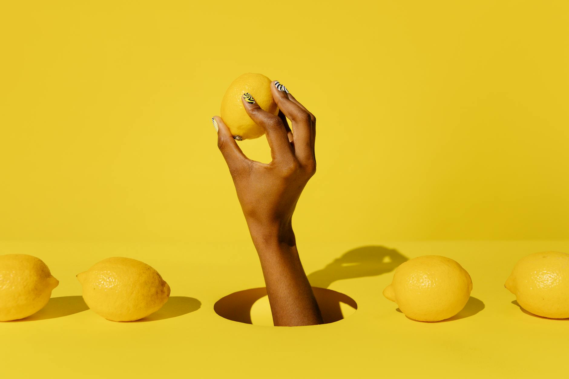 Hand holding a fresh lemon against bright yellow background, symbolizing renewed vitality and fresh approaches to intimacy