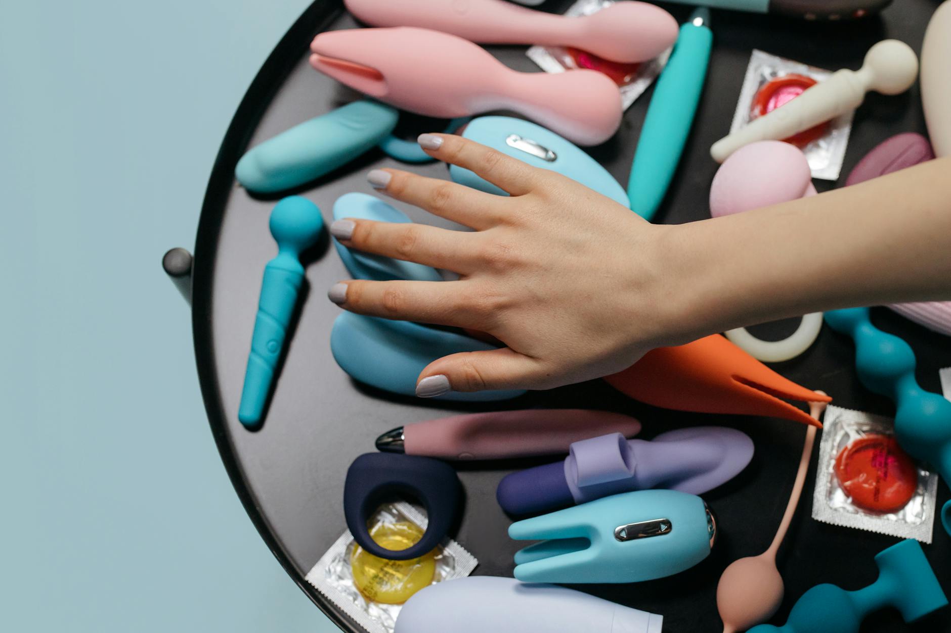 Close-up of hands holding a sleek blue vibrator against a purple background.