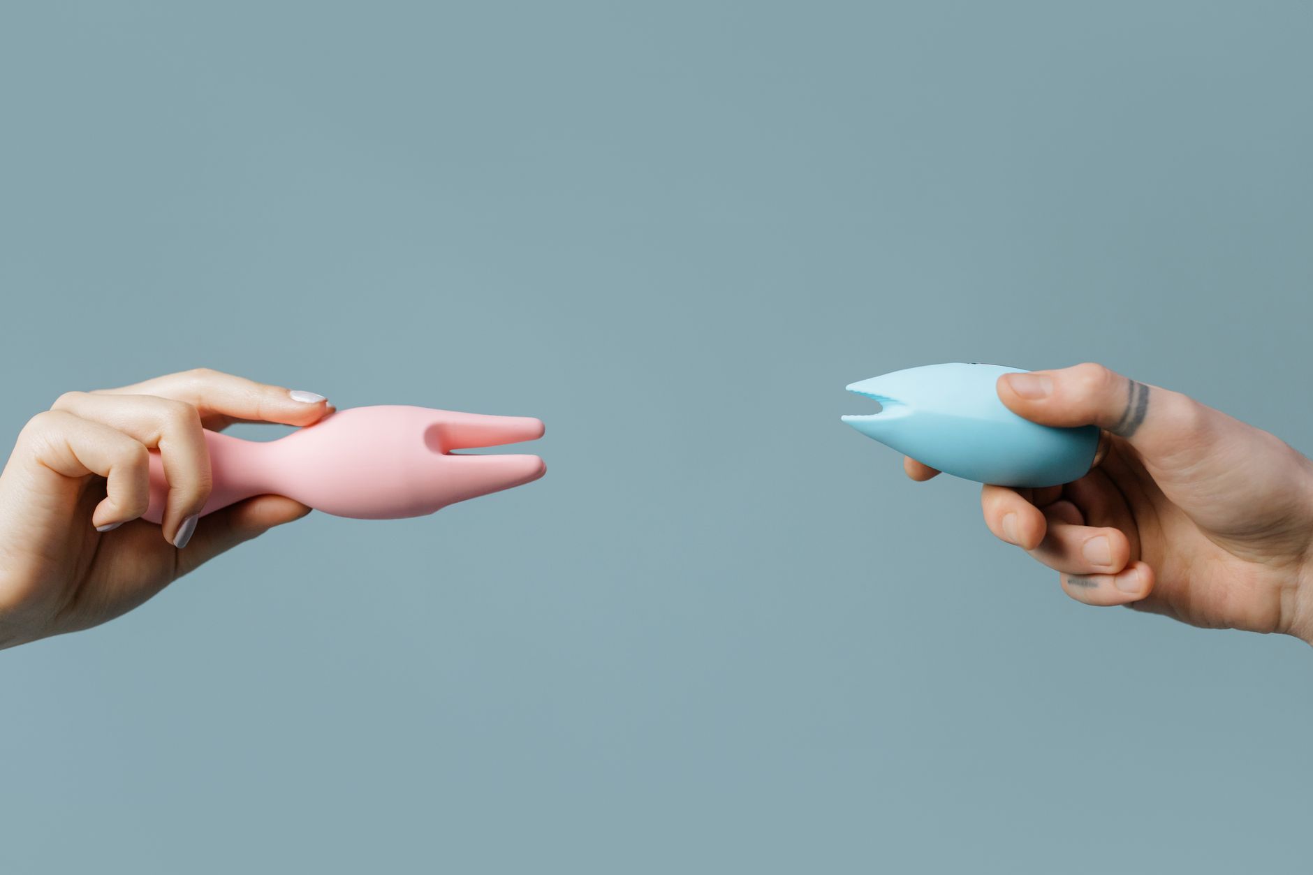 A person holding a blue clitoral suction vibrator, demonstrating comfort and confidence with pleasure technology