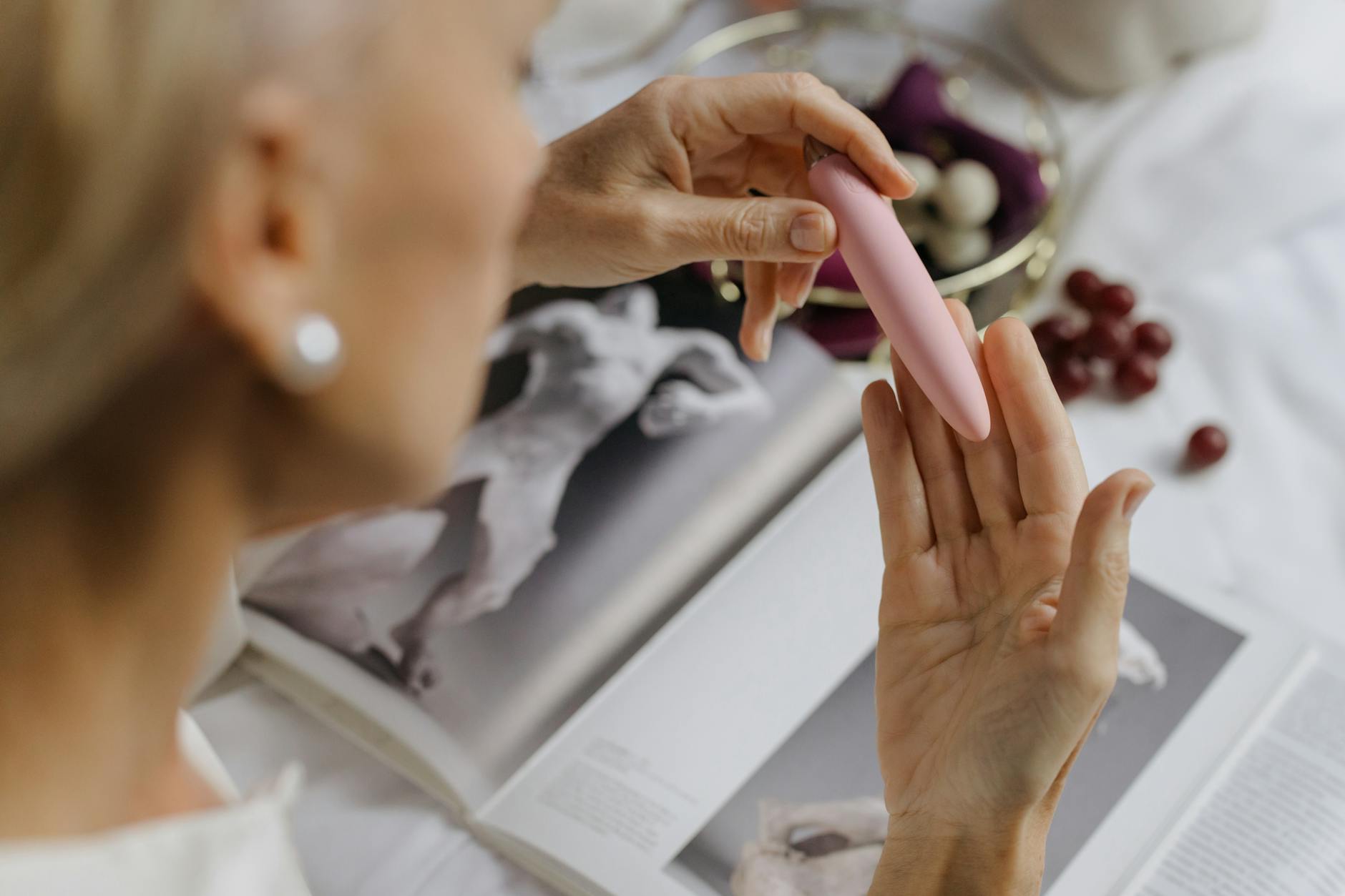 Close-up of a hand holding a vibrator with personal items in background, representing intimate wellness and reclaiming sensation.