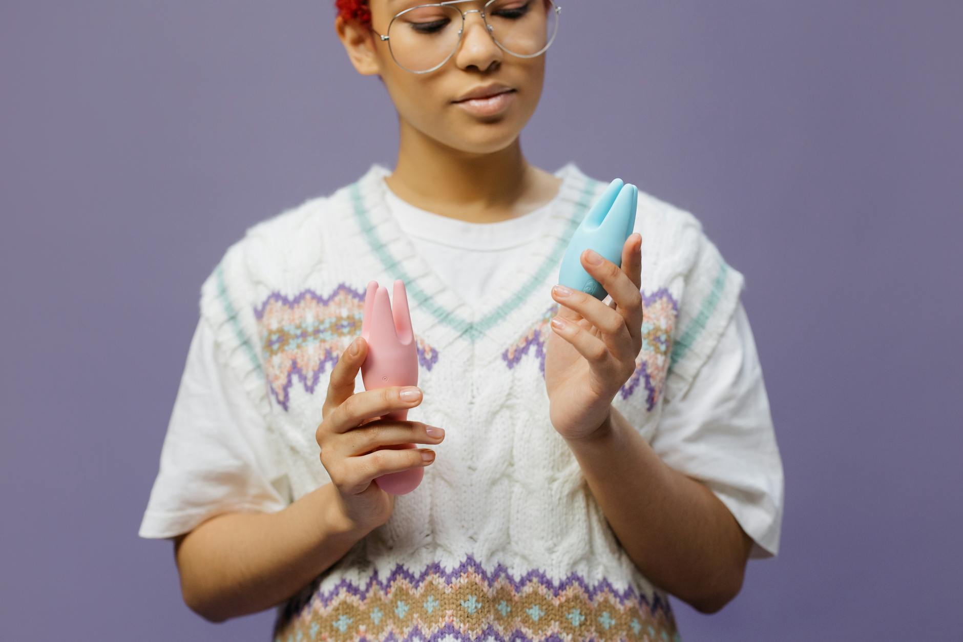 Woman thoughtfully holding colorful clitoral vibrators, representing exploring pleasure during perimenopause